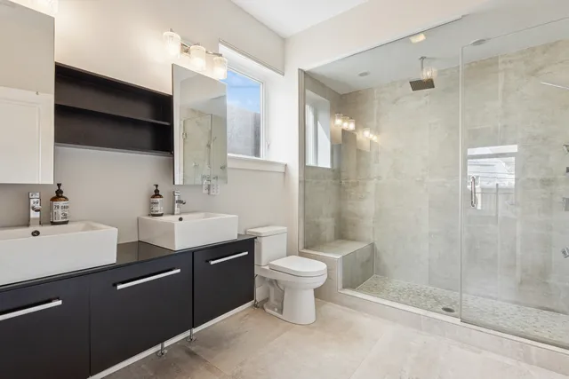 a bathroom with a double vanity sink toilet and shower