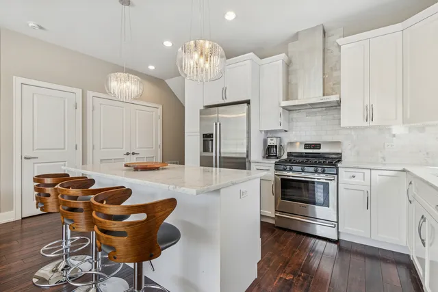 a kitchen with stainless steel appliances kitchen island granite countertop a stove a sink and a white cabinets