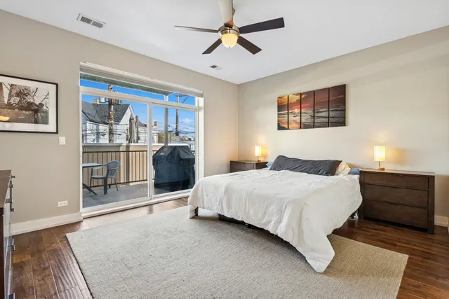 a bedroom with a bed and dresser with wooden floor