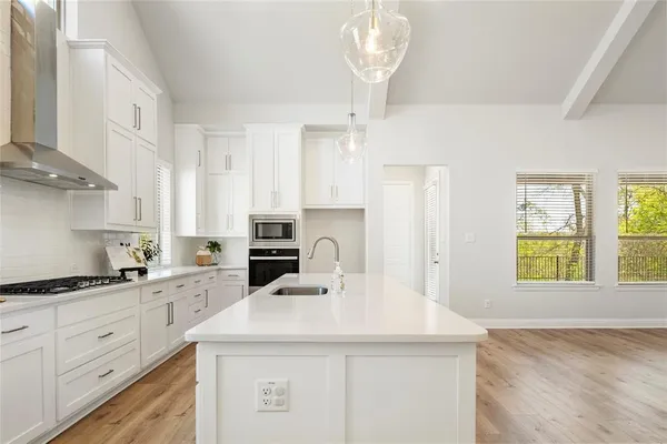 a kitchen with kitchen island granite countertop a sink a counter space appliances and cabinets
