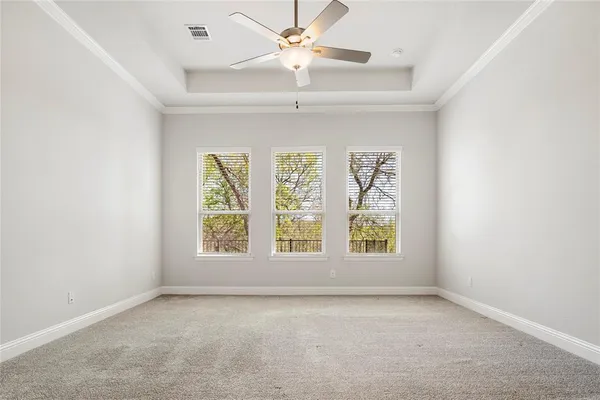 an empty room with windows and ceiling fan