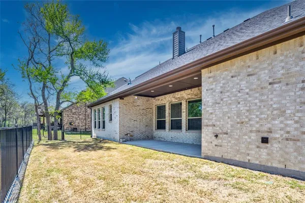 a backyard of a house with large tree and wooden fence