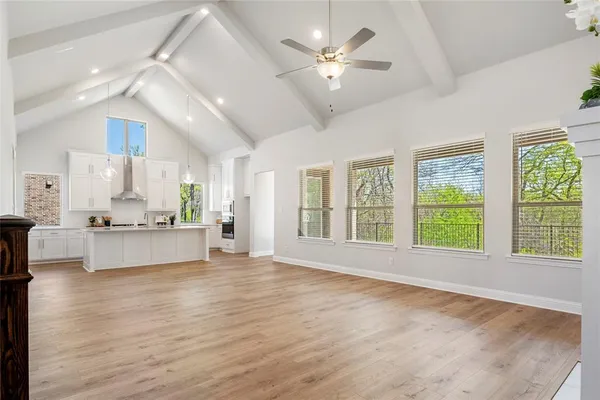a large living room with stainless steel appliances kitchen island granite countertop a stove a refrigerator a sink a dining table and chairs with wooden floor