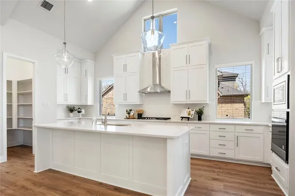 a kitchen with a sink dishwasher a stove and white cabinets with wooden floor