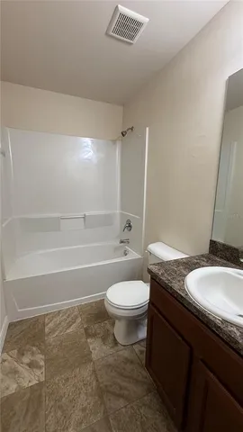a bathroom with a granite countertop toilet a sink and a bathtub