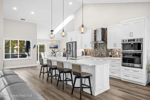 a kitchen with stainless steel appliances kitchen island granite countertop a table chairs sink and cabinets