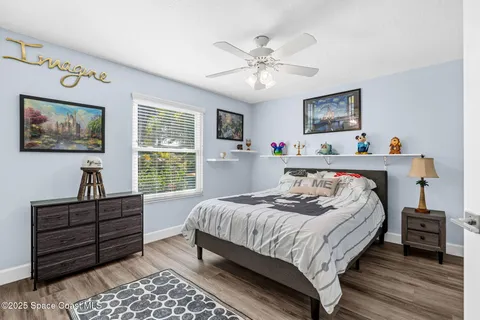 a bedroom with a bed a dresser and painting on the wall