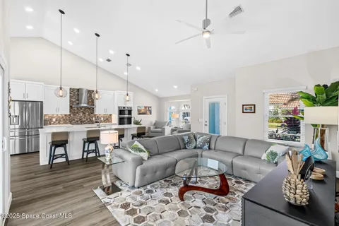 a living room with furniture kitchen view and a wooden floor