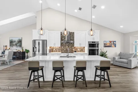 a kitchen with stainless steel appliances kitchen island granite countertop a table chairs and a view of living room