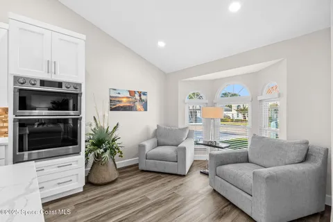 a living room with furniture potted plant and kitchen view