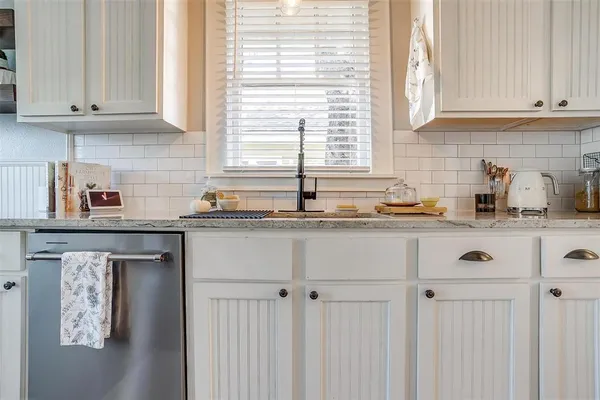 a kitchen with stainless steel appliances granite countertop white cabinets and a window