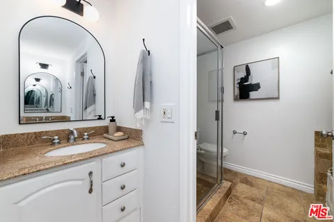 a bathroom with a granite countertop sink and a mirror