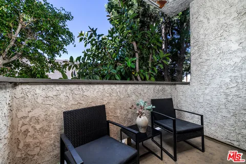 a wooden bench sitting in backside of a house with chairs