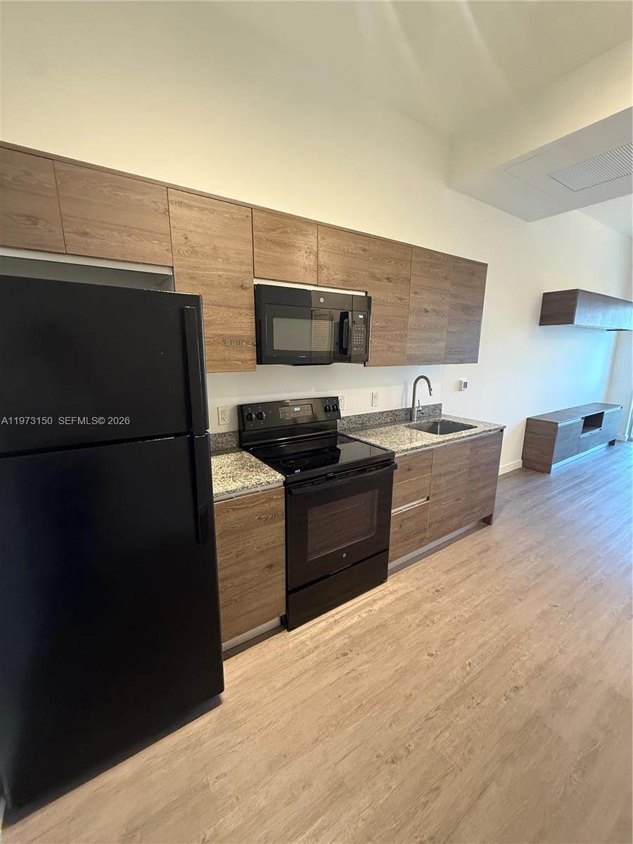 61 Northwest 37th Avenue, Unit 414 Miami, FL 33125 - Photo 2 of 18 a kitchen with a refrigerator and a stove top oven