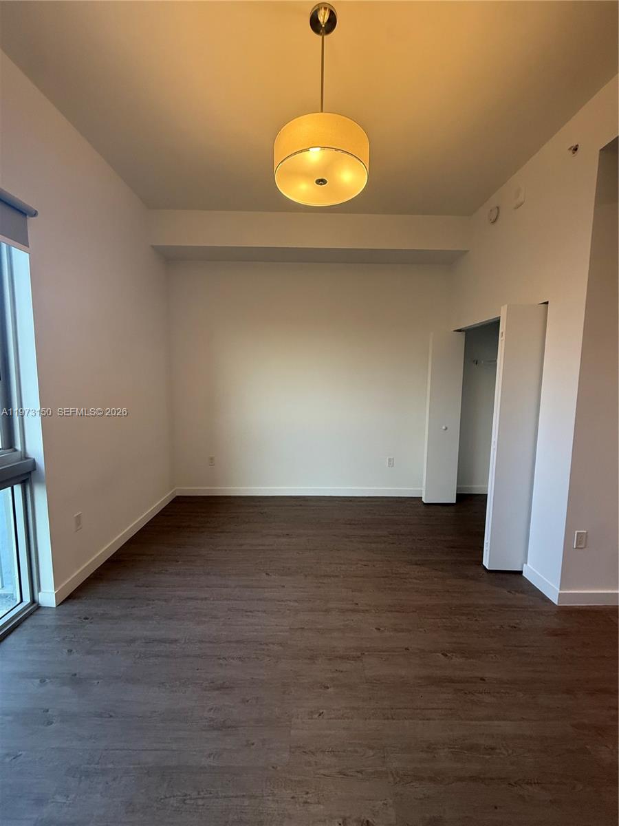 61 Northwest 37th Avenue, Unit 414 Miami, FL 33125 - Photo 8 of 18 a view of an empty room with wooden floor and a window