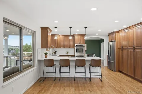 a kitchen with a table chairs refrigerator and wooden floor