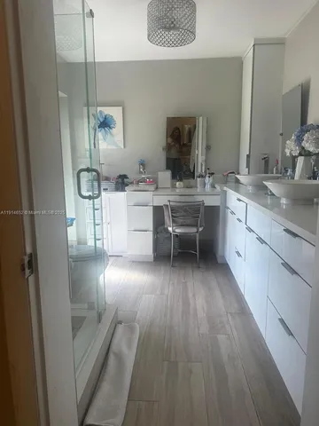 a large kitchen with a sink and wooden floor