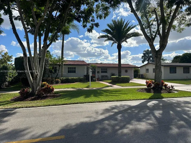 a view of a house with a yard and a large tree