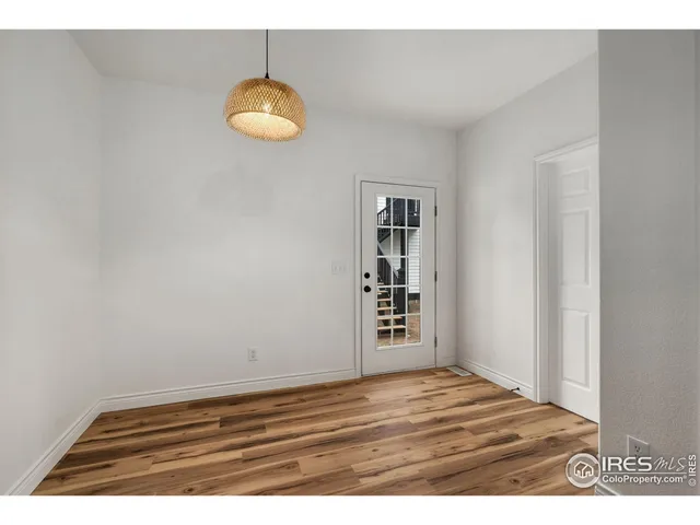 a view of an empty room with window and wooden floor
