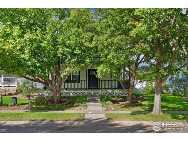 a front view of a house with garden and trees
