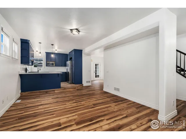 a view of kitchen and empty room with wooden floor