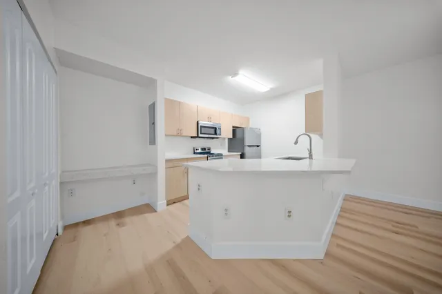 a view of a kitchen with white cabinets and wooden floor
