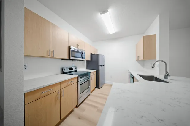 a kitchen with stainless steel appliances granite countertop white cabinets a sink and a stove