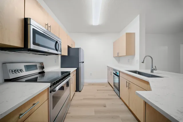 a kitchen with stainless steel appliances a stove microwave and sink