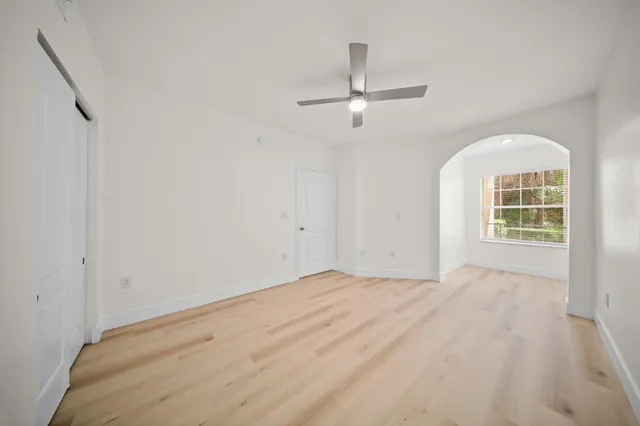an empty room with windows and ceiling fan