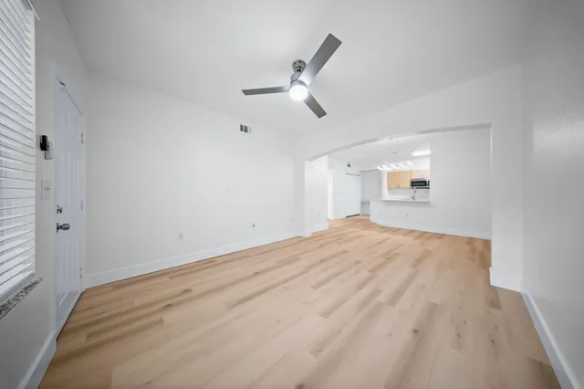 a view of empty room with wooden floor and ceiling fan