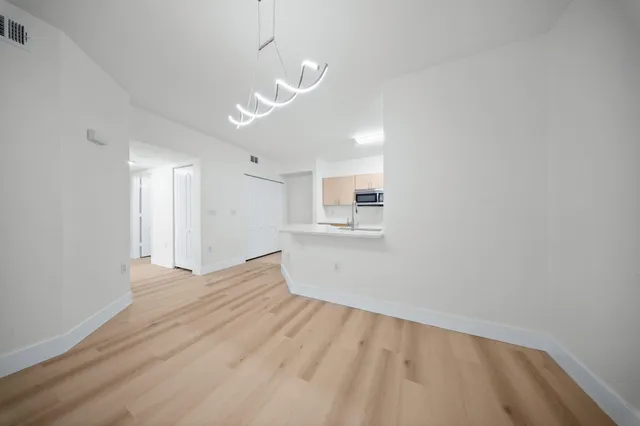 a view of empty room with wooden floor and windows