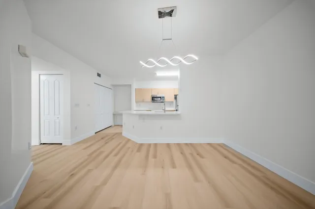 a view of a room with wooden floor and kitchen view