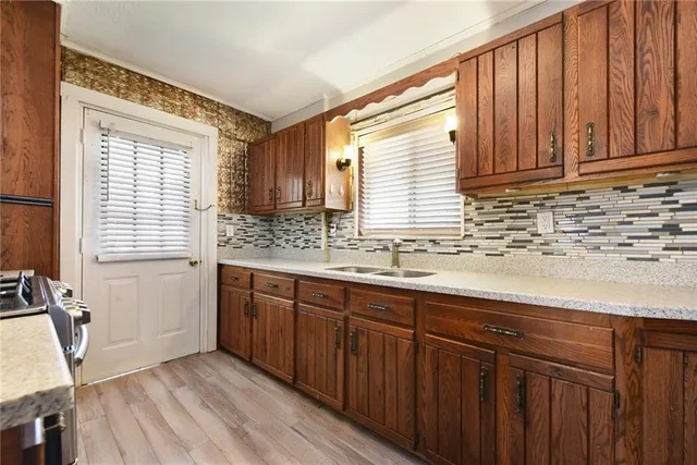 a kitchen with stainless steel appliances granite countertop wooden cabinets a sink and dishwasher with wooden floor