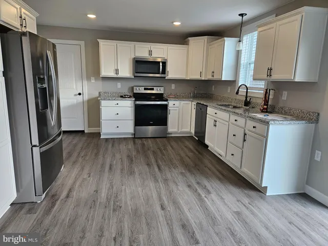 a kitchen with stainless steel appliances a refrigerator sink and wooden floor