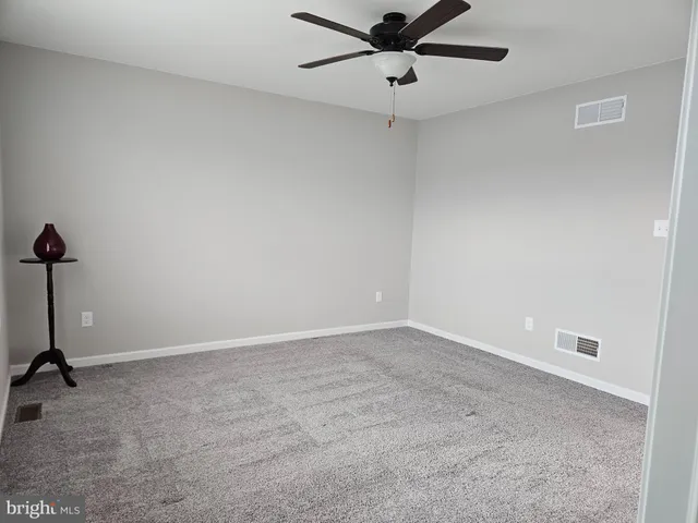 an empty room with a ceiling fan and a window