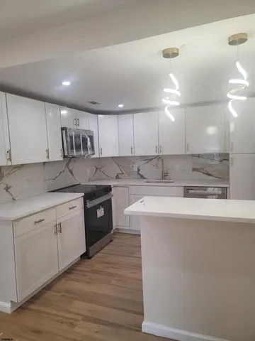 a large kitchen with granite countertop a stove top oven a sink a counter space and cabinets