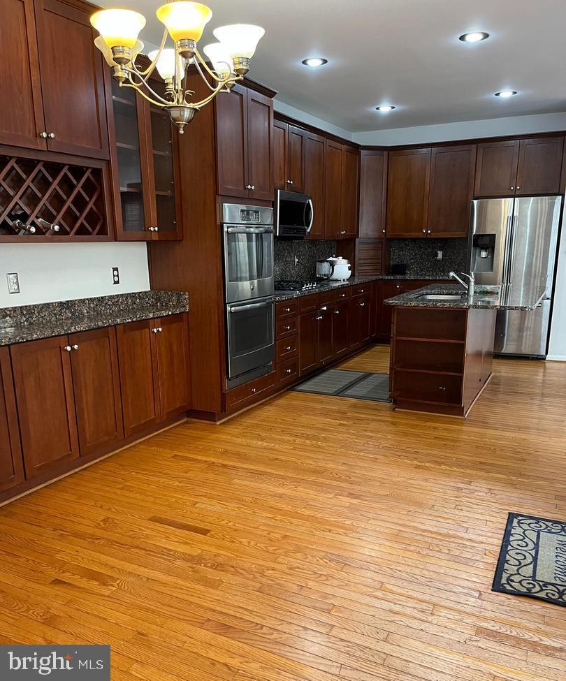 9163 Stone Garden Lorton, VA 22079 - Photo 6 of 25 a kitchen with stainless steel appliances wooden cabinets a stove top oven a sink and dishwasher