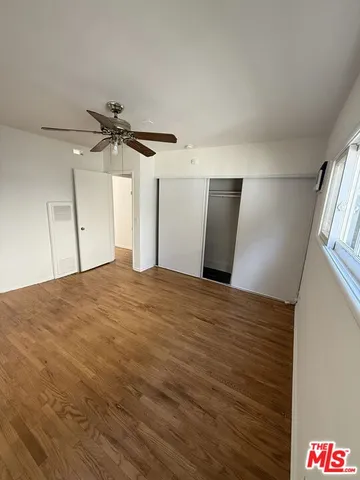 an empty room with wooden floor fan and windows