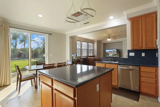 a kitchen with kitchen island granite countertop a sink refrigerator and cabinets