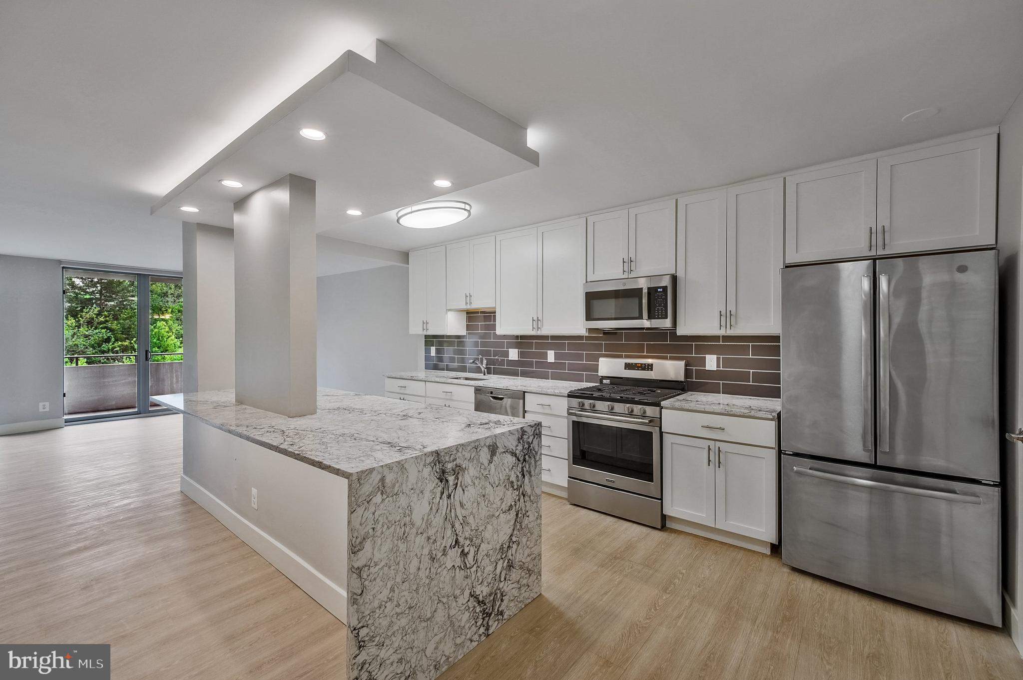 a kitchen with stainless steel appliances granite countertop a refrigerator a stove a sink and a microwave