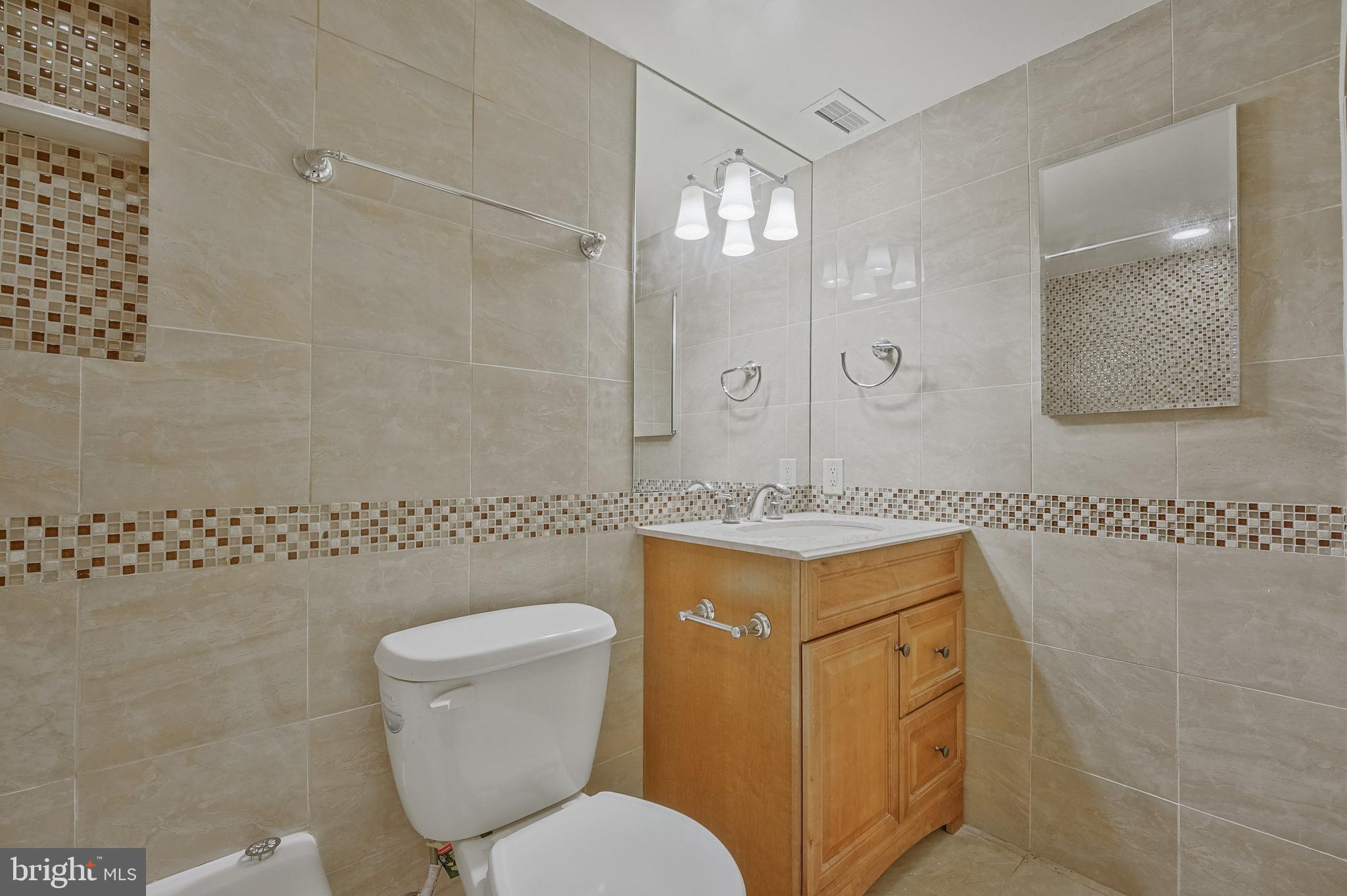 5101 River Road, Unit 618 Bethesda, MD 20816 - Photo 26 of 46 a bathroom with a granite countertop toilet sink and mirror