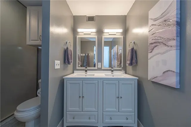 a bathroom with a granite countertop sink a toilet and a mirror