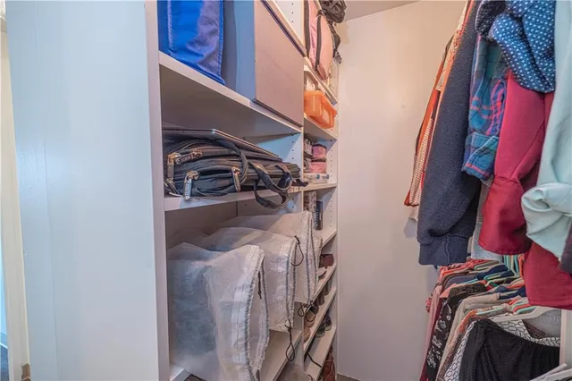 a view of walk in closet with clothes and shoes