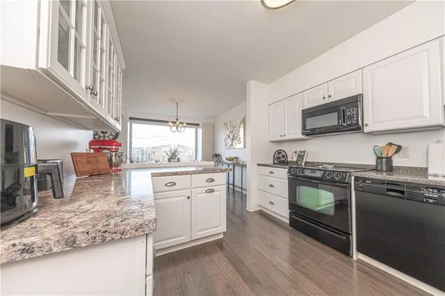 a kitchen with stainless steel appliances granite countertop a stove a sink dishwasher and a microwave oven with white cabinets