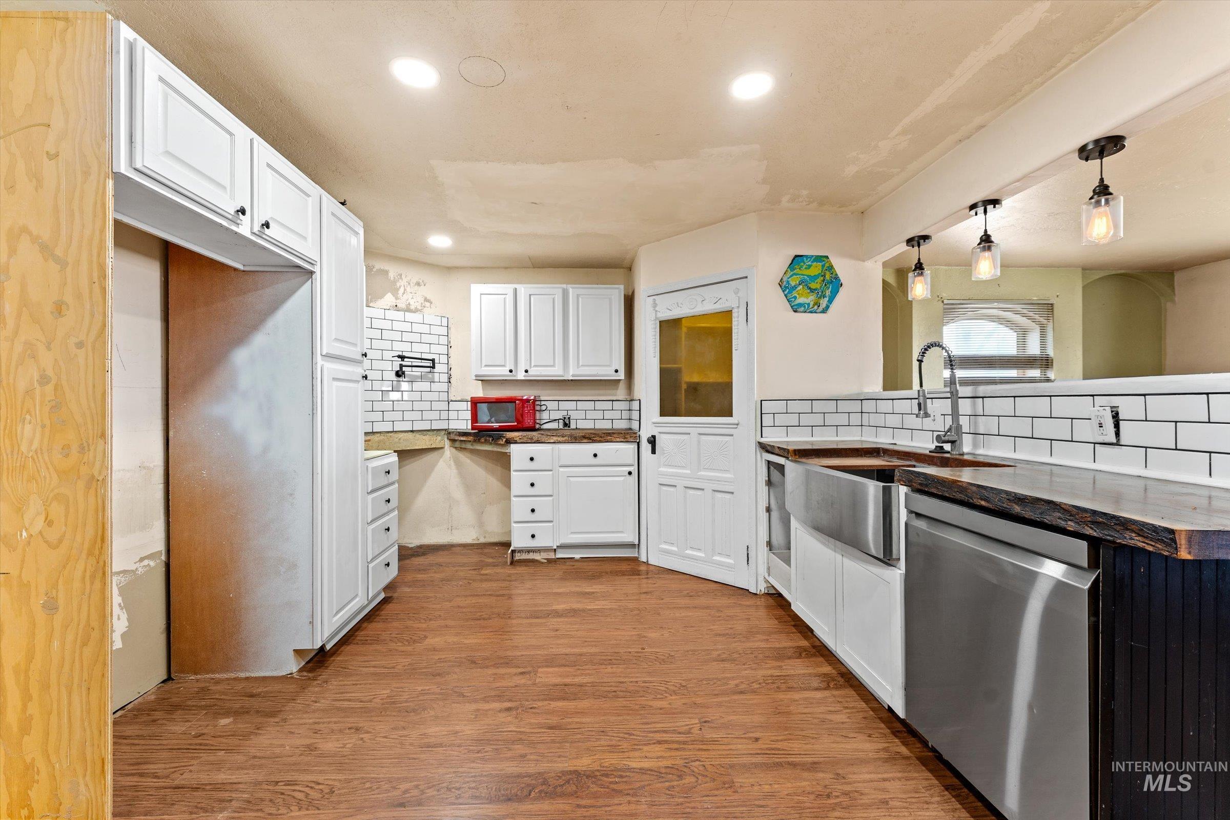 6267 Deer Flat Road Nampa, ID 83686 - Photo 4 of 50 Kitchen with backsplash, dishwasher, dark wood finished floors, white cabinets, and pendant lighting