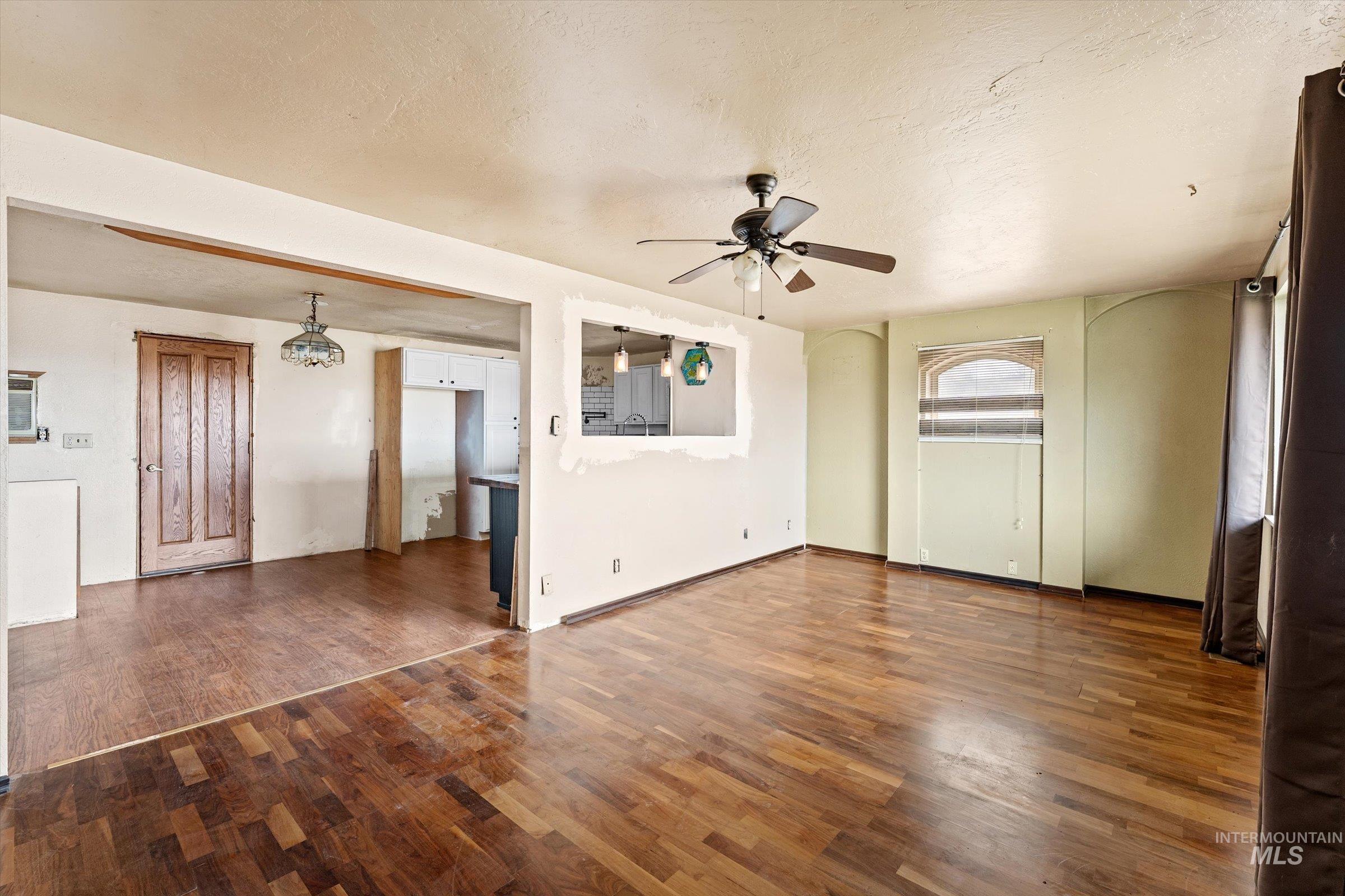 6267 Deer Flat Road Nampa, ID 83686 - Photo 6 of 50 Unfurnished living room featuring a ceiling fan, dark wood-style flooring, and a textured ceiling