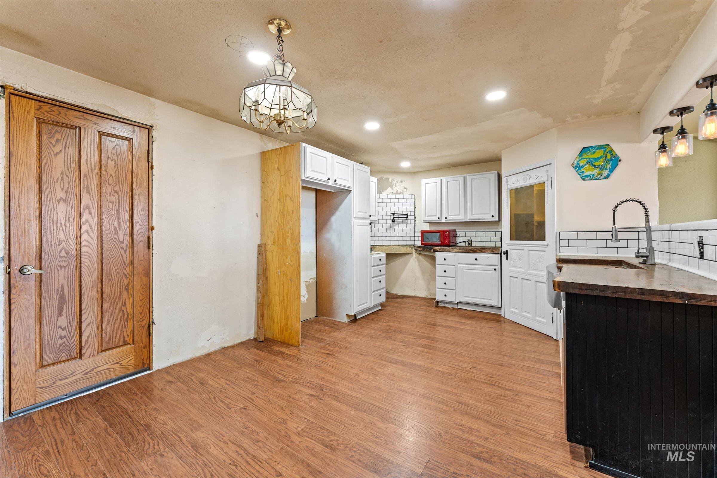 6267 Deer Flat Road Nampa, ID 83686 - Photo 8 of 50 Kitchen featuring decorative backsplash, pendant lighting, light wood-type flooring, white cabinetry, and wooden counters