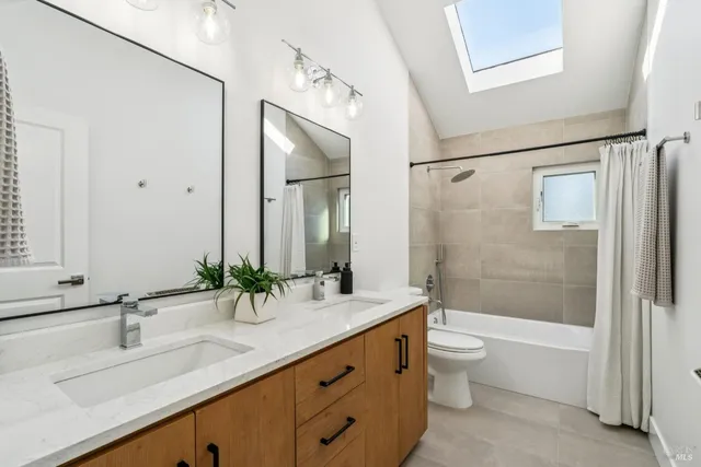 a bathroom with a double vanity sink toilet mirror and shower