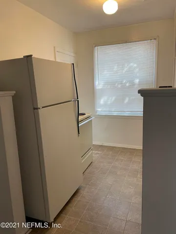 a view of a refrigerator in kitchen and an empty room