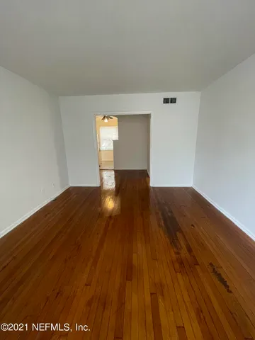 a view of a big room with wooden floor and windows